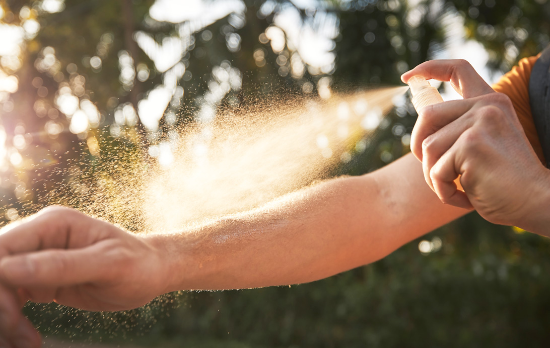 Person spraying arm with bug spray