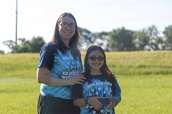 Lily and her mom showing her pump in front of a field.