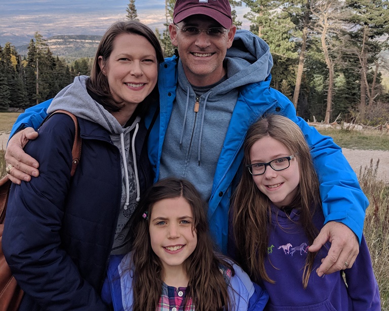 Clayton and his family standing near trees.