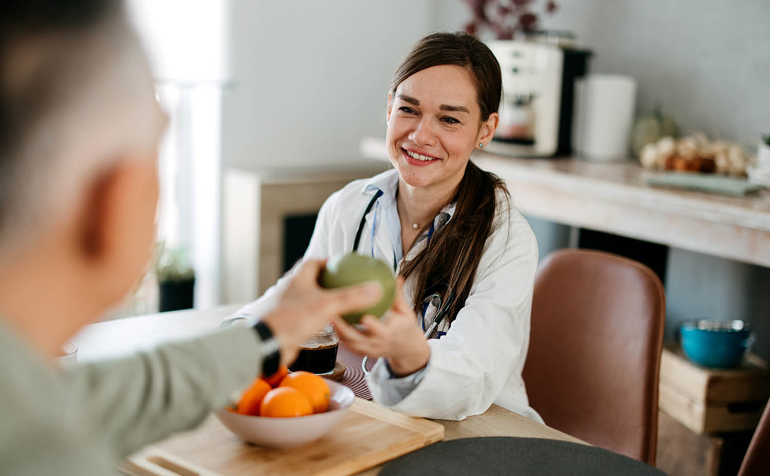 a nutritionist hands a piece of fruit to a patient