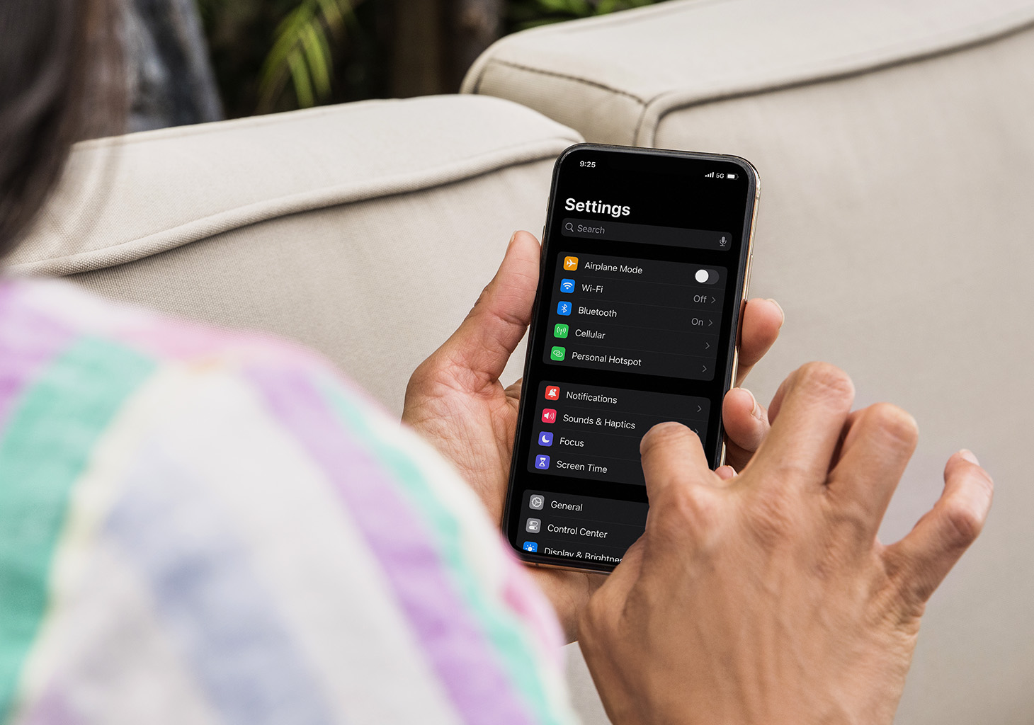 Woman holding phone showing iOS Settings