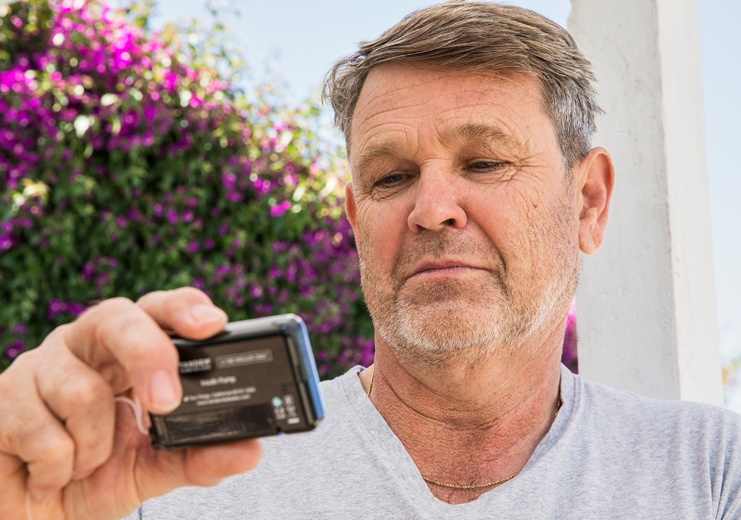 Man Looking at t:slim X2 Insulin Pump and Pressing Screen On Button